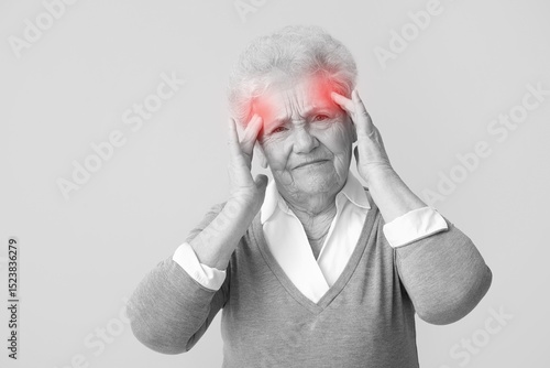 Senior woman suffering from headache on grey background
