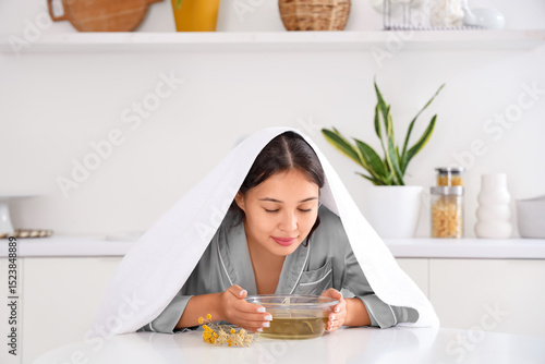 Принти на полотні Young Asian woman doing steam inhalation at table in kitchen
