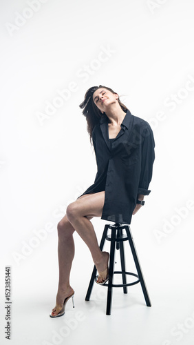 Young woman sitting on furry stool wearing transparent heels and smartwatch