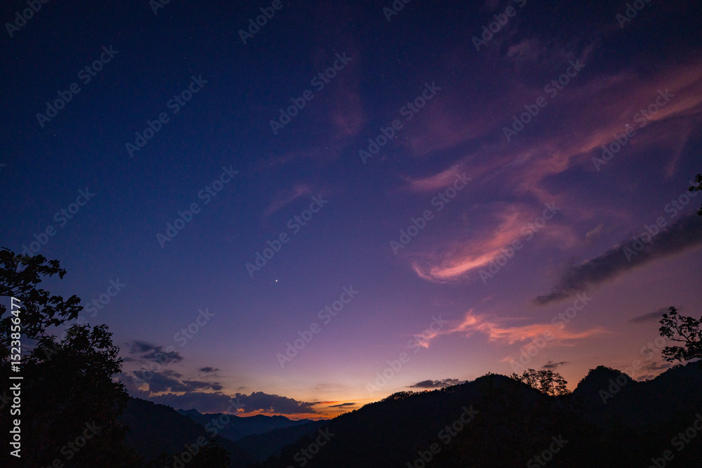 Obraz premium Milky Way above mountains at night in autumn. Landscape with mountain valley, low clouds, purple starry sky with milky way. The Milky Way shines on a cold night in the north of Thailand