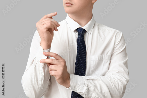 Young man in stylish white collar shirt and necktie on grey background