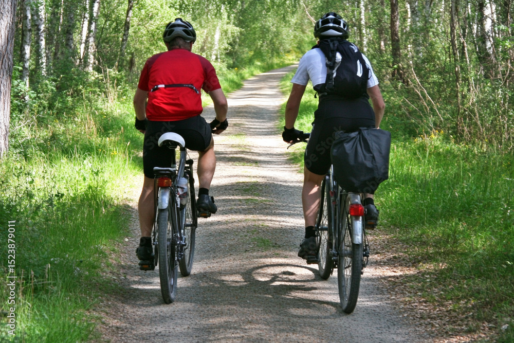 Fototapeta premium Cyclists exploring a peaceful trail through lush greenery