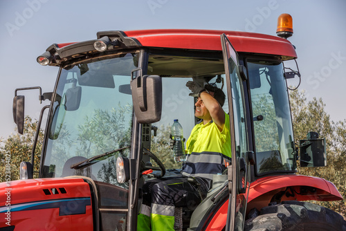 Farm worker in tractor struggles with summer heat while providing safety and hydration