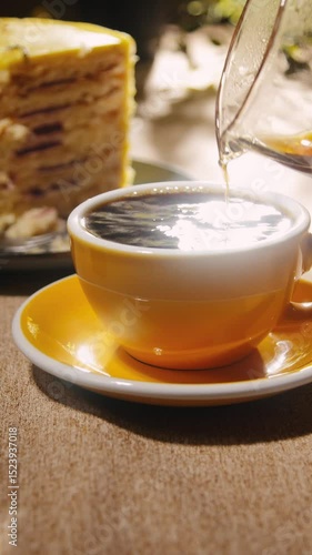 Pouring coffee into the yellow ceramic cup vertical close up