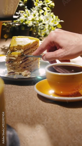 Forking a piece of layered cake with the coffee in front