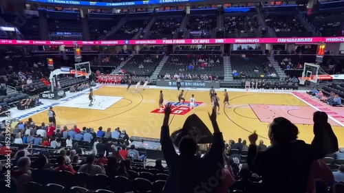Exciting Basketball Game Atmosphere: Fans Cheer and Wave Flags at a Thrilling Match