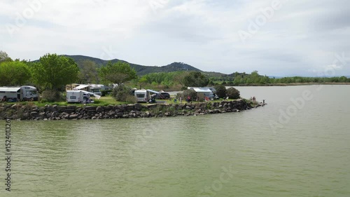 Europe, Italy, Umbria, 06,08,2025 drone  view of naturist camping with camper tents on the lakeside in Pontile Sant'arcangelo  Trasimeno lake , summer destination attraction 