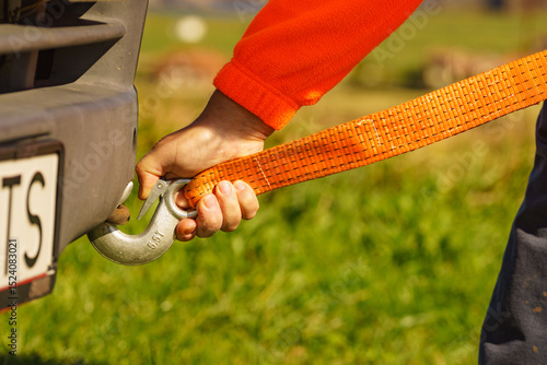 Fototapeta Male hand attaching towline to car