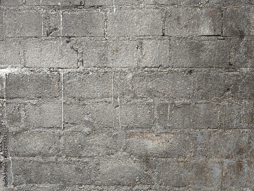 Full frame close-up of an old, weathered grey cement block wall with visible mortar lines and stains, providing a gritty, textured background ideal for industrial or urban themes