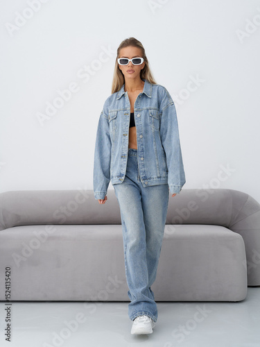 Blonde model showcases stylish denim outfit in modern studio setting