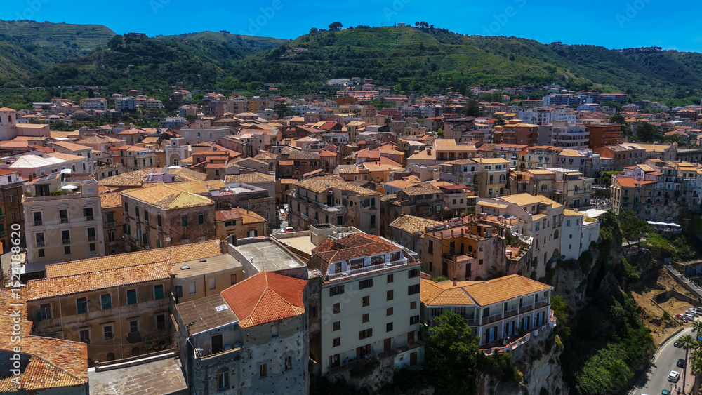 Fototapeta premium Panoramic view of Tropea, a charming town perched on a cliff, featuring traditional houses with red tile roofs, overlooking the Tyrrhenian Sea in Calabria, Southern Italy