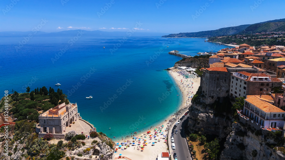 Obraz premium Aerial view of Tropea, Calabria, with turquoise Tyrrhenian Sea, sandy beach, colorful umbrellas, and Sanctuary of Santa Maria dell'Isola