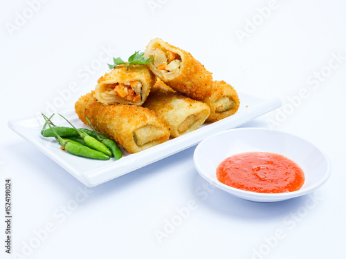 Fotografia Indonesian risoles filled with vegetables, served with fresh green chilies on a white plate