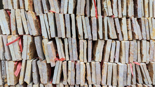 Stacked stone tiles with rustic texture and red ties, forming a natural geometric pattern