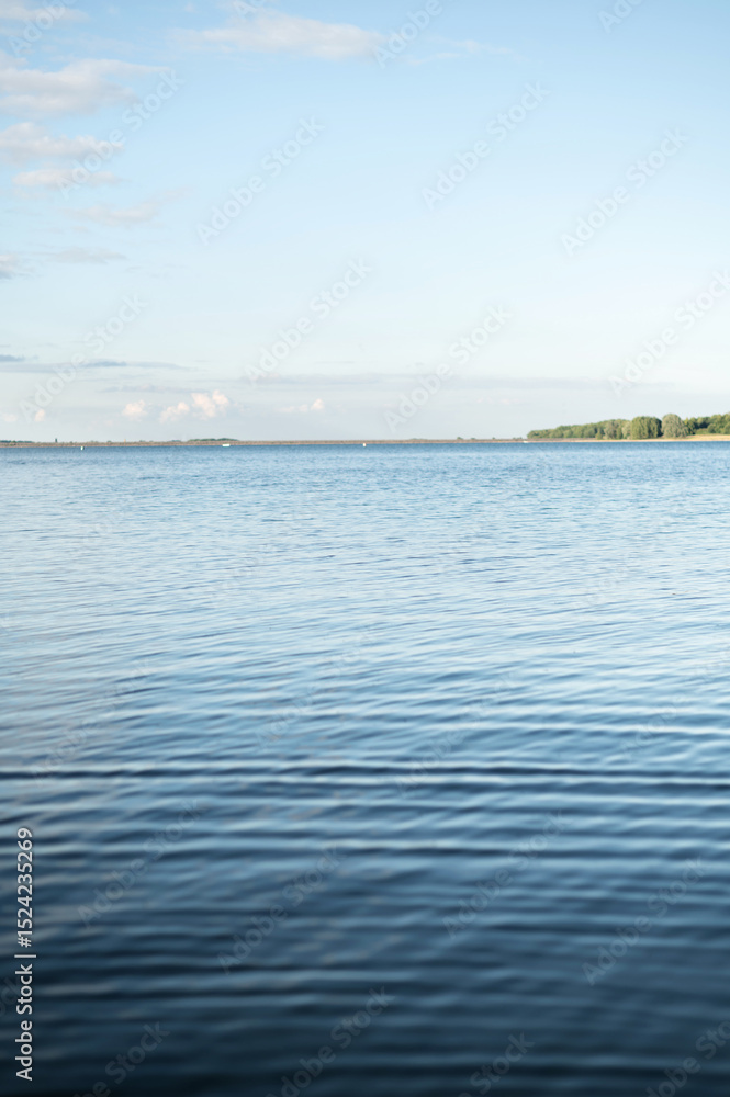 Serene landscape featuring a lake with gentle ripples on the surface and a distant shoreline under a clear sky. Serene landscape featuring a lake with gentle ripples on the surface and a distant shoreline under a clear sky.