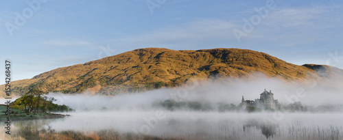 Castle on a reflective lake on a misty morning in Scotland