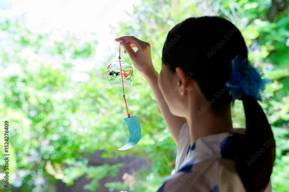 Obraz premium 夏の縁側で風鈴を眺める浴衣姿の女性の静かな時間