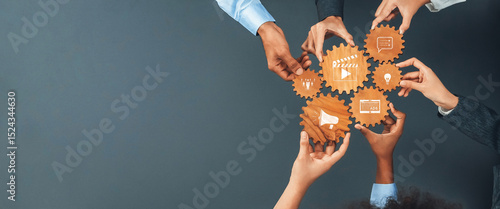 This image portrays a vibrant teamwork scenario where diverse hands hold wooden gears adorned with icons, representing collaboration and innovative business strategies. Amity