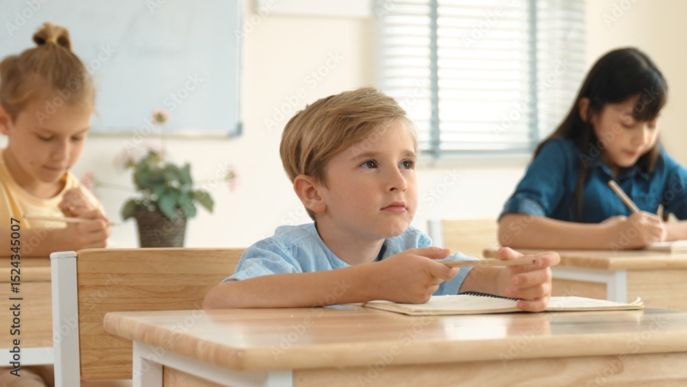 Caucasian boy raising hand for asking and answering teacher surrounded by diverse children studying at classroom. Happy student working together, voting, volunteering, calling instructor. Pedagogy. Caucasian boy raising hand for asking and answering teacher surrounded by diverse children studying at classroom. Happy student working together, voting, volunteering, calling instructor. Pedagogy.