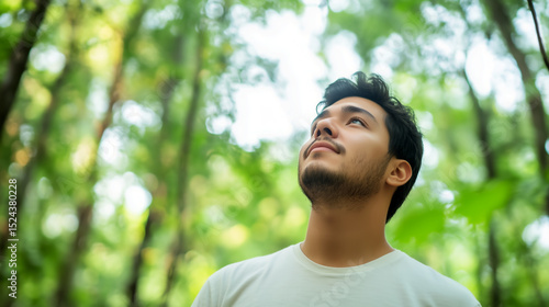 Young man admires nature in a lush forest during daytime in summer