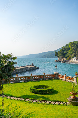 A scenic view of the Gulf of Trieste from Miramare Castle’s garden, featuring manicured lawns, palm trees