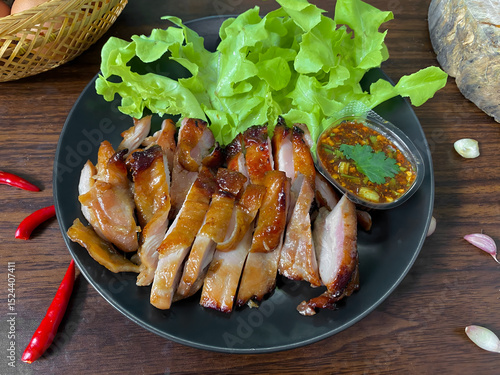 Thai Grilled Chicken with Spicy Dipping Sauce and Fresh Lettuce on Black Plate – Traditional Thai Cuisine