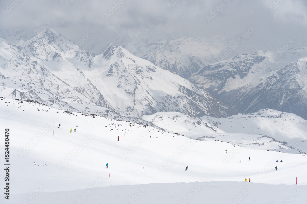 Obraz premium Skiers descending a snowy slope on Mount Elbrus, Kabardino-Balkaria, Russia, with majestic snow-covered peaks in the background