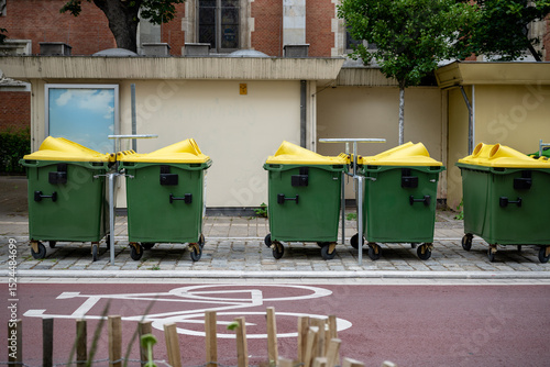 Fotografie green recycling containers with yellow lids on city street, concept of urban was
