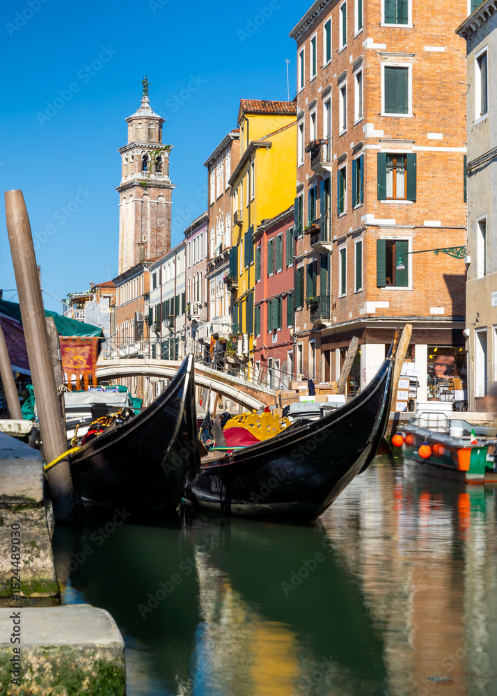 Fototapeta premium Gondolas on Venice canal with colorful buildings and bell tower