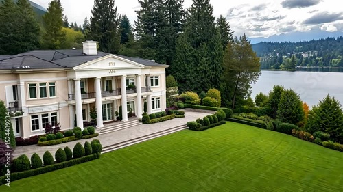 Elegant waterfront mansion surrounded by lush greenery and serene lake views at sunny summer day