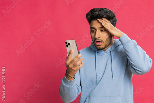 Obraz na plátně Upset sad Indian man use smartphone typing browsing, play game, loses, surprised by sudden lottery results bad fortune loss fail unlucky news