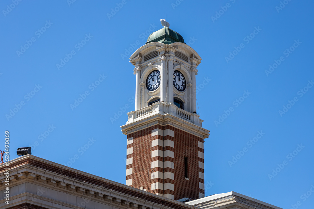 Fototapeta premium Low angle view of an exterior cupola and clock tower on a exterior brick building in bright sunlight with blue sky