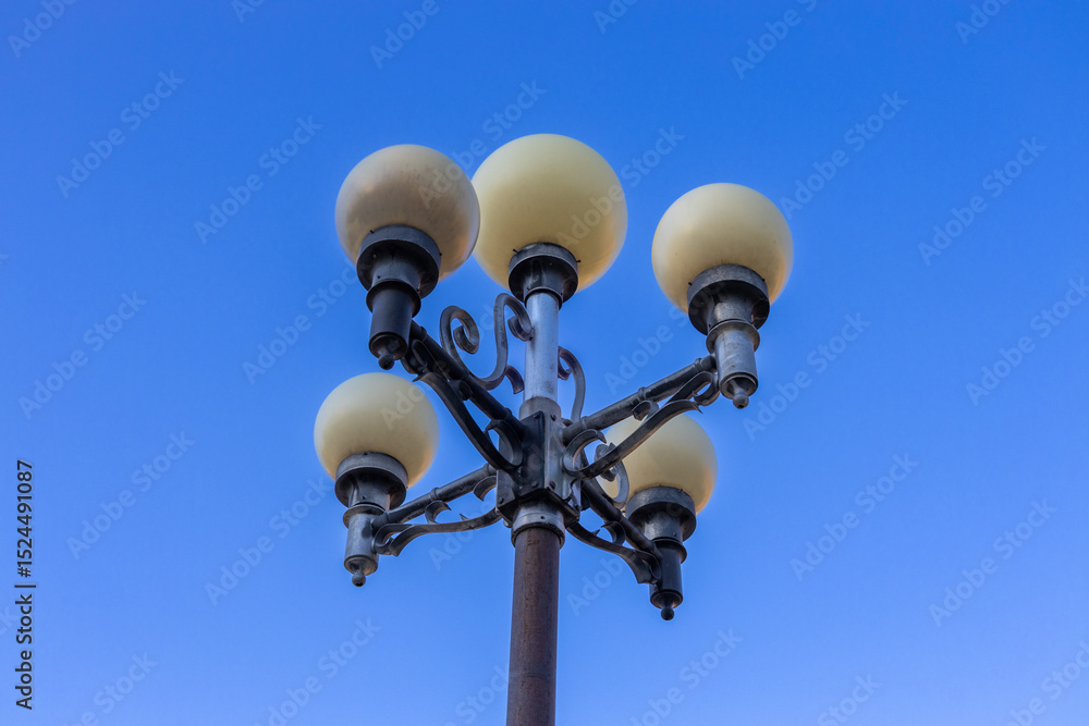 Low angle, abstract view of a 20th century ornamental street lamp, with clear blue sky background Low angle, abstract view of a 20th century ornamental street lamp, with clear blue sky background