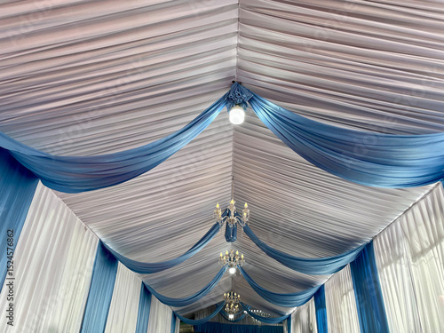 Party tent ceiling with wavy white and blue fabric decorated with small round lights