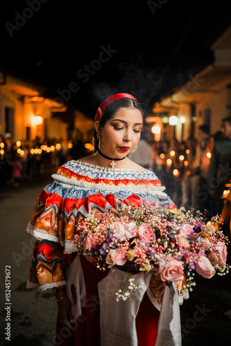 Mujer sahumadora vestida con traje típico tradicional participa en una procesión nocturna durante la Semana Santa en Popayán, Colombia. Sostiene un ramo de flores mientras esparce sahumerio 