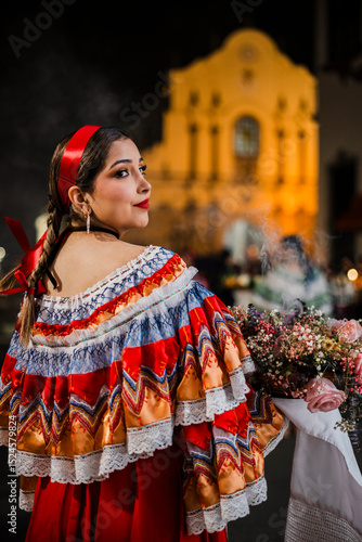 Mujer sahumadora vestida con traje típico tradicional participa en una procesión nocturna durante la Semana Santa en Popayán, Colombia. Sostiene un ramo de flores mientras esparce sahumerio 