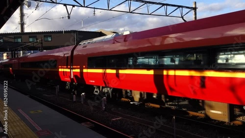 駅のプラットホームに入線する艶やかな赤色の電車