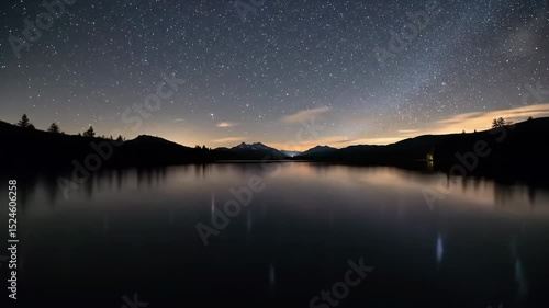 Starry night reflection on tranquil lake with silhouette mountains