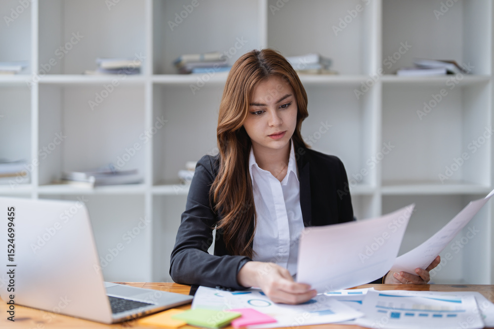 Focused businesswoman analyzes documents at her desk in a bright office space Focused businesswoman analyzes documents at her desk in a bright office space