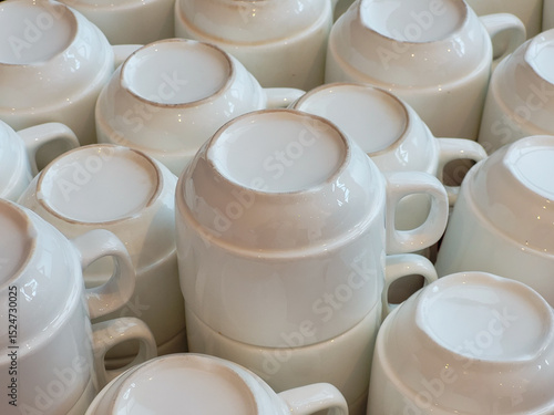 Clean white ceramic coffee mugs stacked upside down in bulk, arranged neatly for service in a café, hotel, or buffet environment, ready for use.