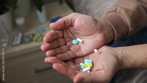 A large handful of pills fall into the hands of a man