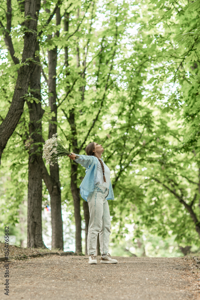 Woman Flowers Happiness: Girl holds daisies, enjoys nature, in a park at daytime, feels joyful. Woman Flowers Happiness: Girl holds daisies, enjoys nature, in a park at daytime, feels joyful.