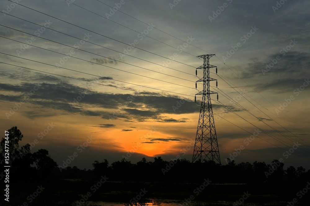 Fototapeta premium High voltage power lines silhouetted against a dramatic sunset sky, transmitting electricity and industrial energy