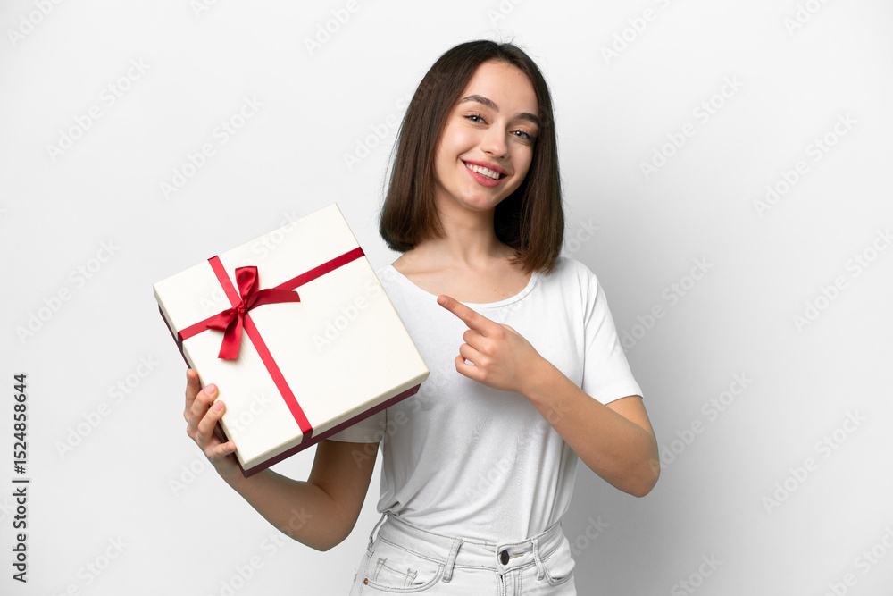 Young Ukrainian woman holding a gift isolated on white background and pointing it Young Ukrainian woman holding a gift isolated on white background and pointing it