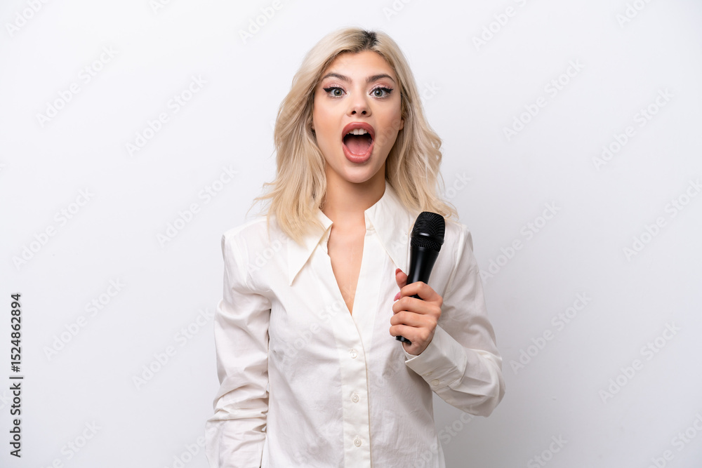Young singer woman picking up a microphone isolated on white background with surprise facial expression Young singer woman picking up a microphone isolated on white background with surprise facial expression