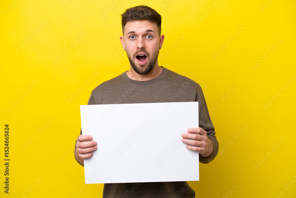 Young caucasian man isolated on yellow background holding an empty placard with happy expression Young caucasian man isolated on yellow background holding an empty placard with happy expression