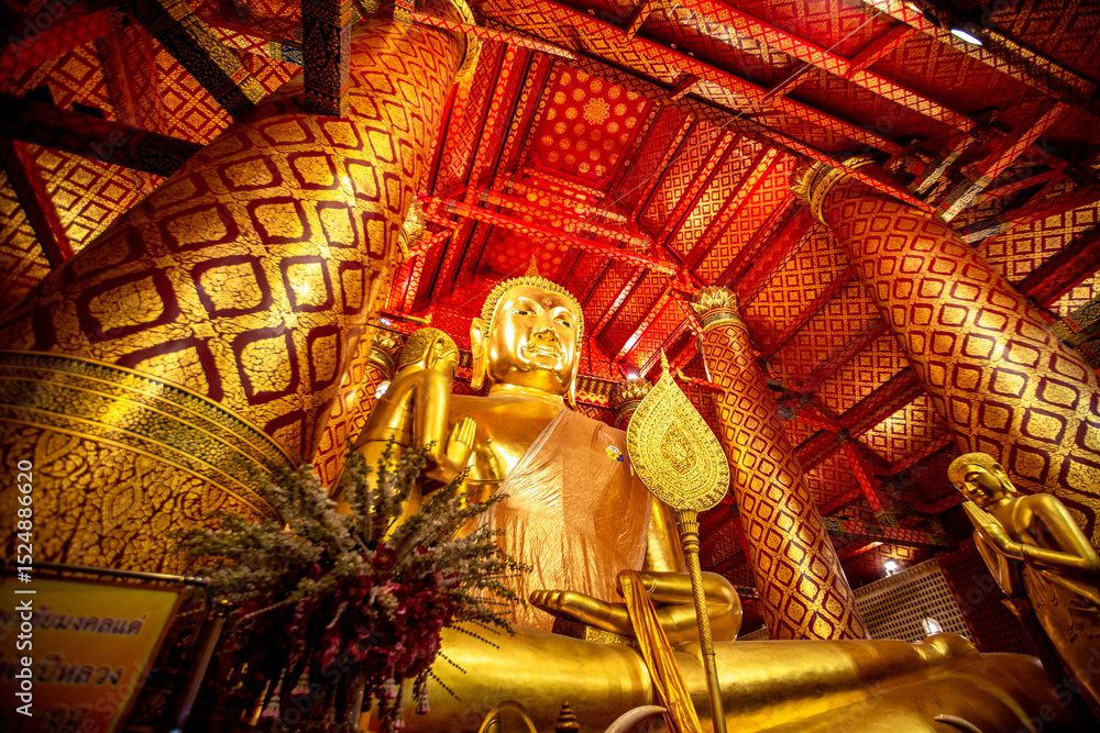 Fototapeta premium Background of religious tourist attractions in Ayutthaya, Thailand. Wat Phanan Choeng, Wat Luang Pho To, has an ancient golden-yellow Buddha statue. Tourists always come to make merit.