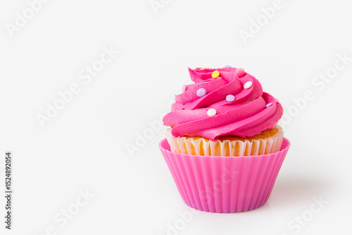 Brightly pink decorated cupcake with icing swirls and colorful sprinkles