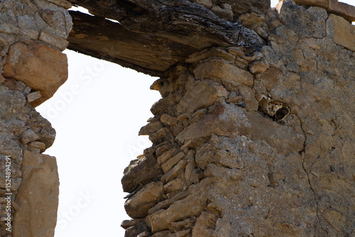 Quadro em tela A close-up view of an opening in a crumbling stone wall, featuring an old wooden
