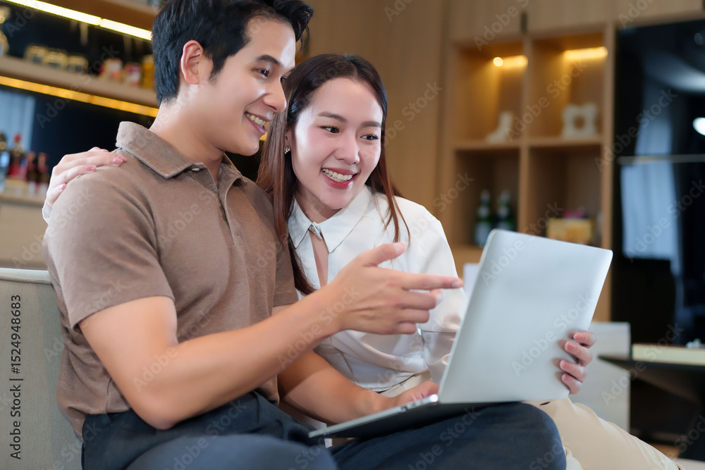 Fototapeta premium Asian Adult Couple Smiling and Using Laptop Together At Home Happy Adult Couple Online Shopping Asian Adult Couple Communication